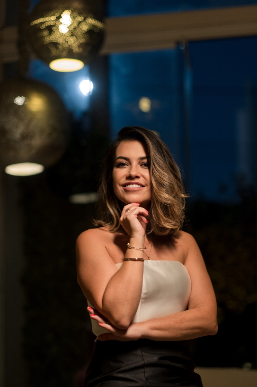 Dra. Denise Ozores, sorrindo em retrato com a mão apoiada no queixo.