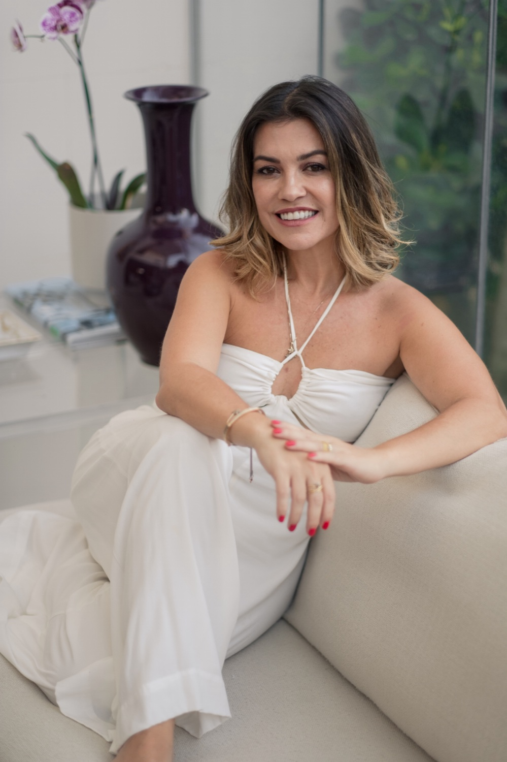 Dra. Denise Ozores sentada em uma poltrona, sorrindo.